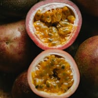 High angle of halves of fresh juicy passion fruits with yellow pulp in wicker bowl